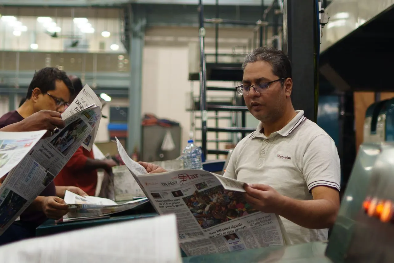 Notícias, curiosidades e tendências em um só lugar: Homens lendo jornais em ambiente de trabalho, com páginas abertas sobre a mesa e foco em notícias do dia em redação ou sala de imprensa.